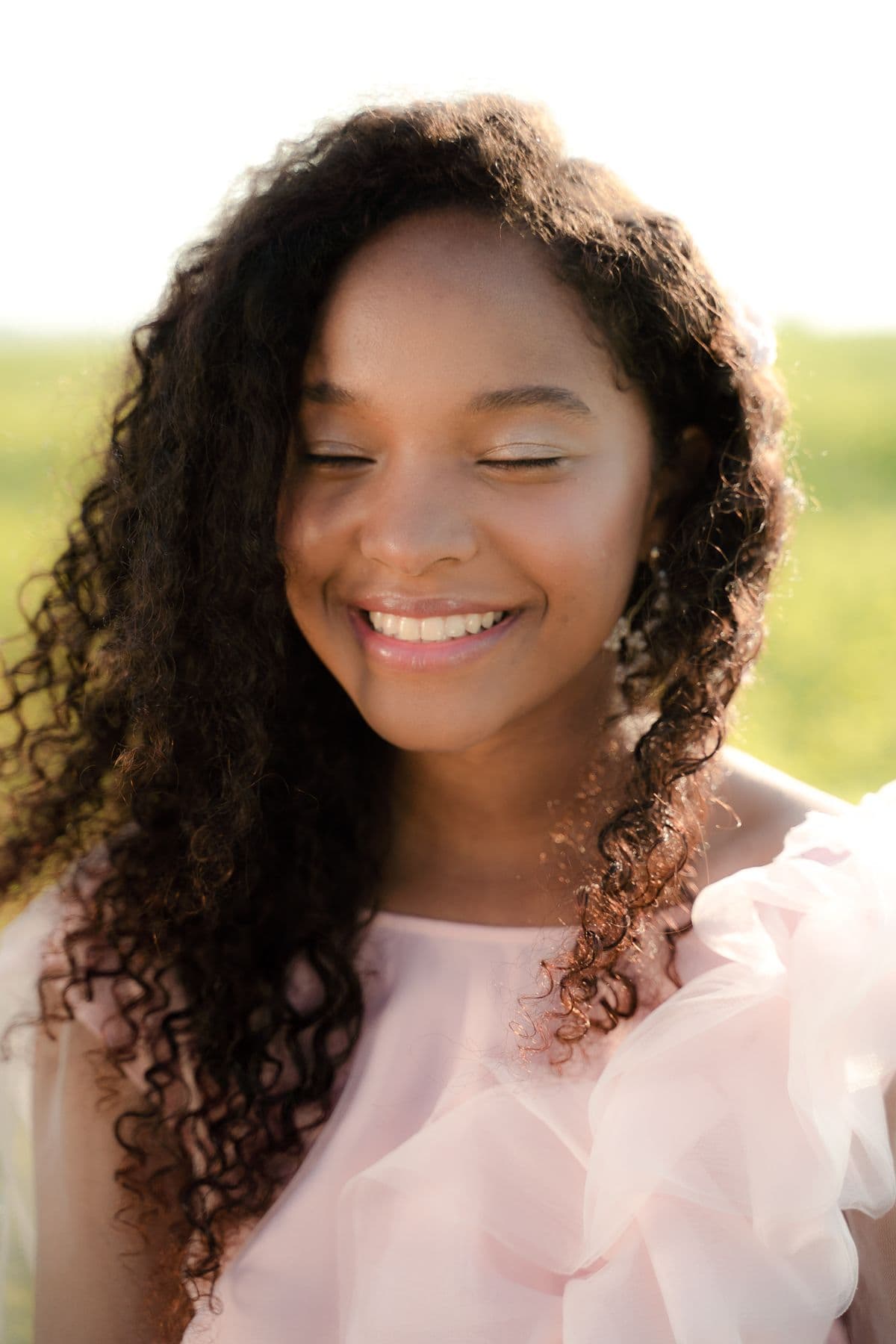 A person smiling gently with their eyes closed in warm golden light